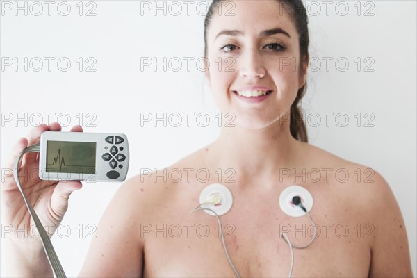 Lady with electrodes holding monitor with cardiogram