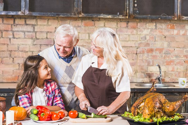 Grandparents cooking turkey with granddaughter