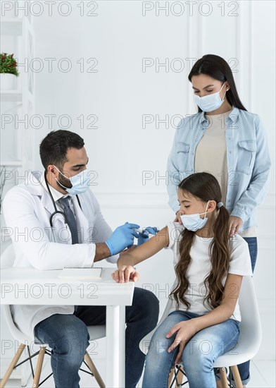 Doctor vaccinating little girl that s supported by her mother