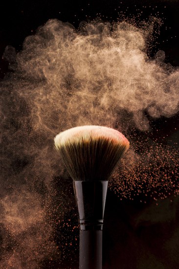 Makeup brush with peach color powder splash