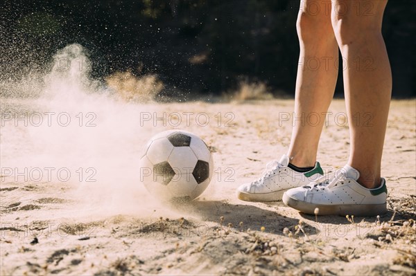 Crop athletic legs standing by football outdoors