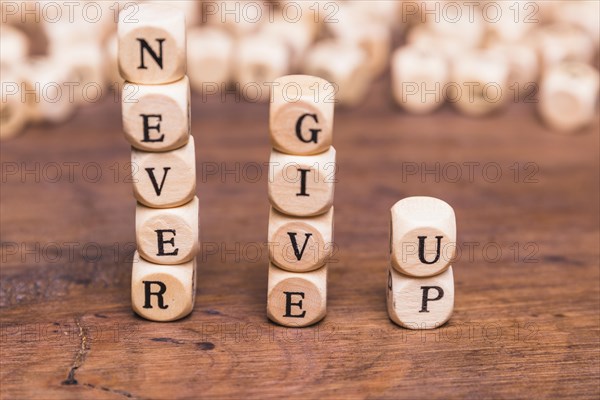 Stacked wooden blocks with word never give up wooden desk