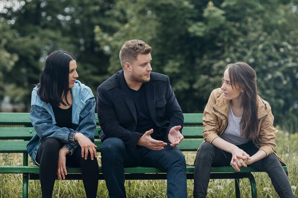 Conflicting people sitting bench talking