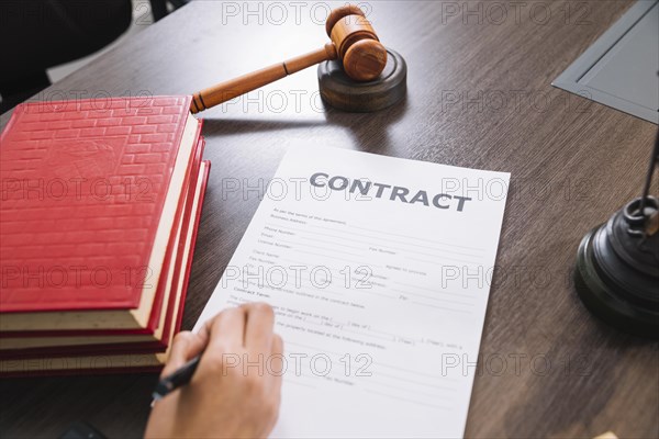 Person writing document table with books gavel