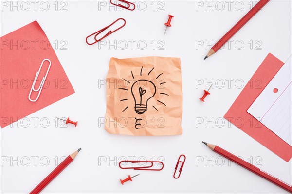 Sticky note with drawn light bulb office supplies white background