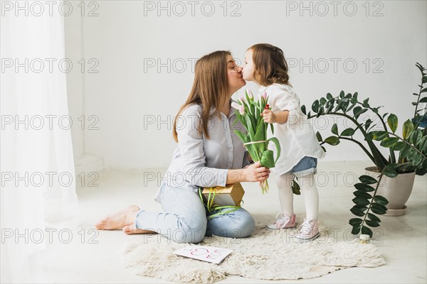 Mother with flowers daughter kissing