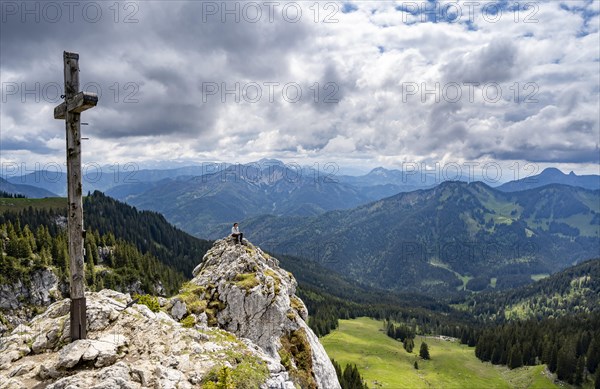 Mountaineer sitting at the summit of Taubenstein with summit cross