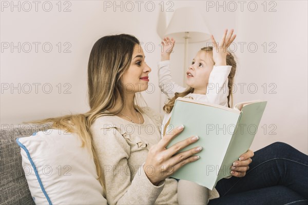 Girl telling story mom while reading book