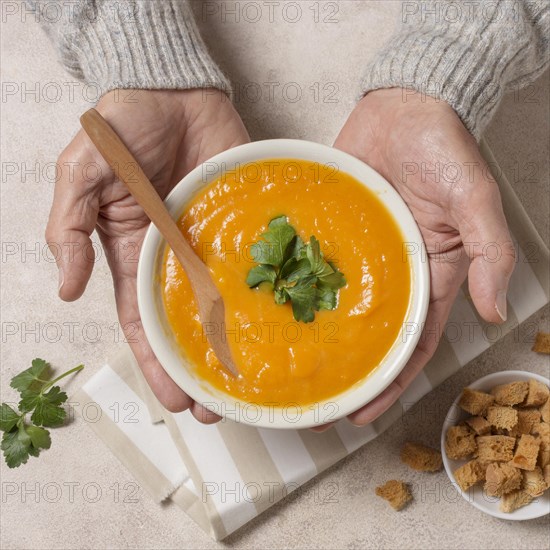 Close up hands holding cream soup bowl