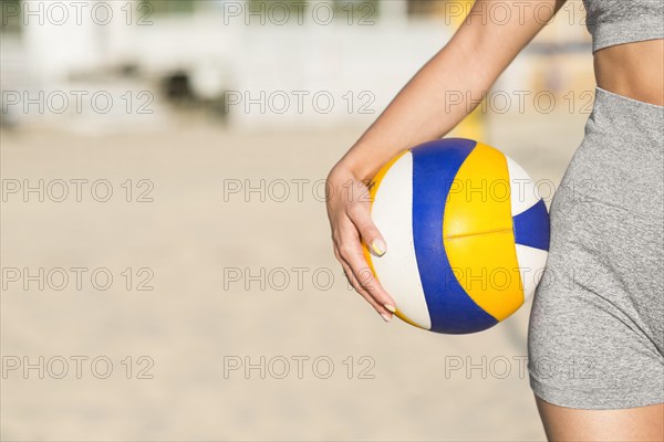 Front view female volleyball player beach holding ball with copy space