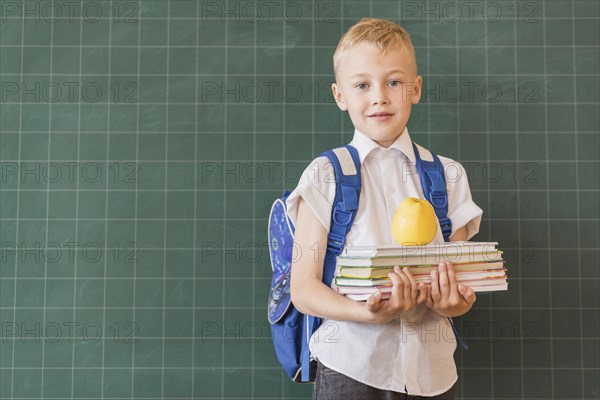 Boy with backpack books near blackboard