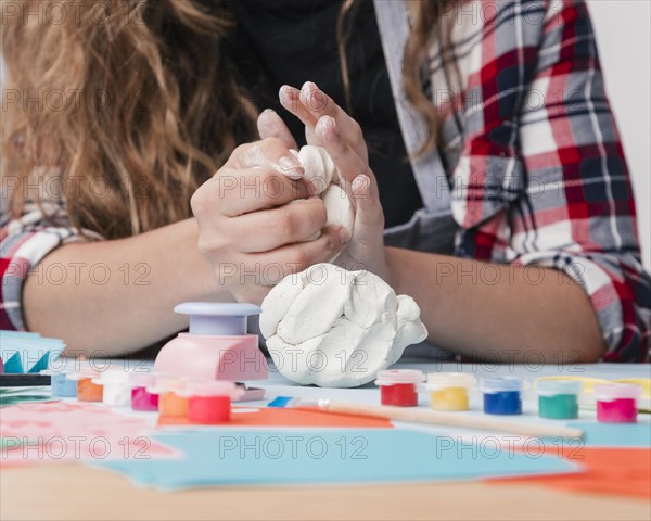 Close up young woman hand kneading white clay