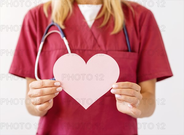 Front view female doctor with stethoscope holding paper heart