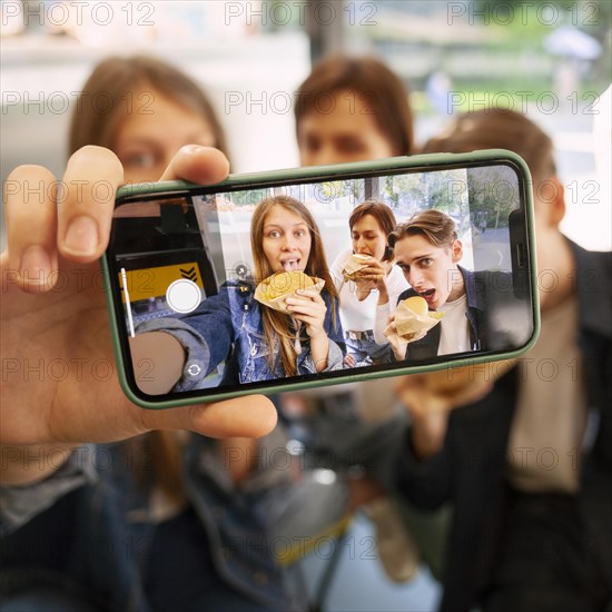 Group friends taking selfie together while eating fast food
