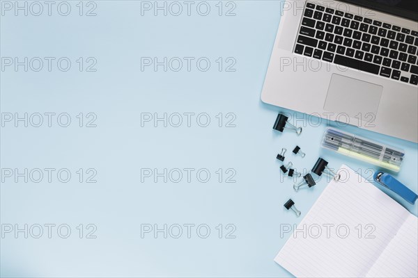 Elevated view laptop stationeries blue backdrop