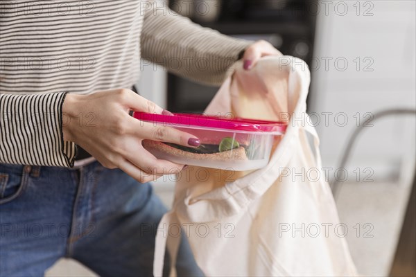 Front view woman puts lunch boxes bag