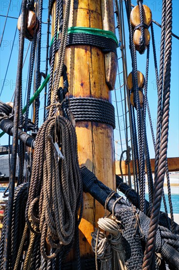 Mast of old wooden Age of sail sailing ship with ropes cordage and shroud
