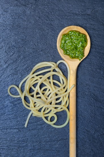 Pesto in cooking spoon and spaghetti