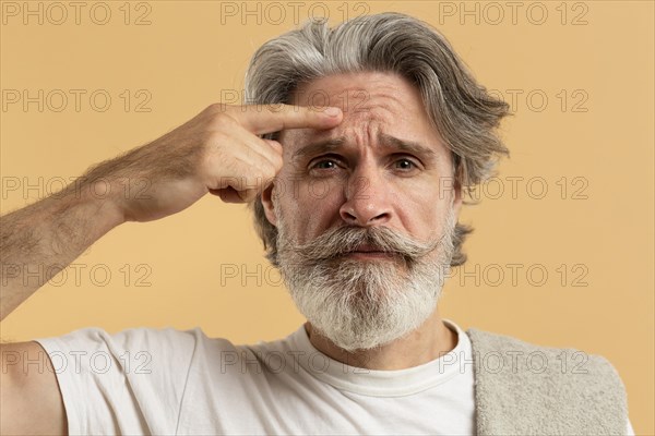 Front view elder man with beard pointing out wrinkles