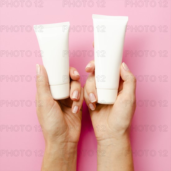 Close up hands holding cream bottles