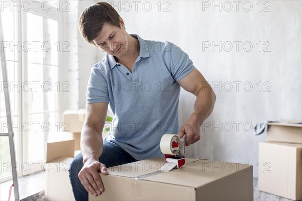 Man using scotch tape box secure it moving out