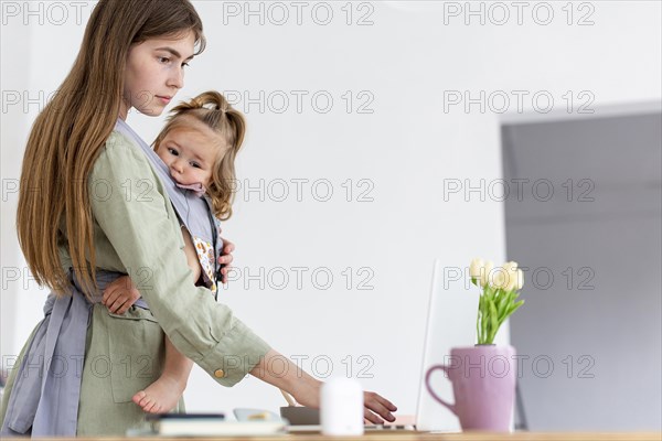 Mother holding girl while working