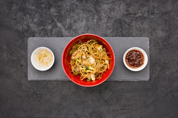 Overhead view delicious noodles bowl with sauce marinated ginger black slate stone