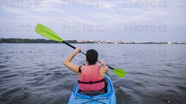 Rear view male kayaker paddling kayak