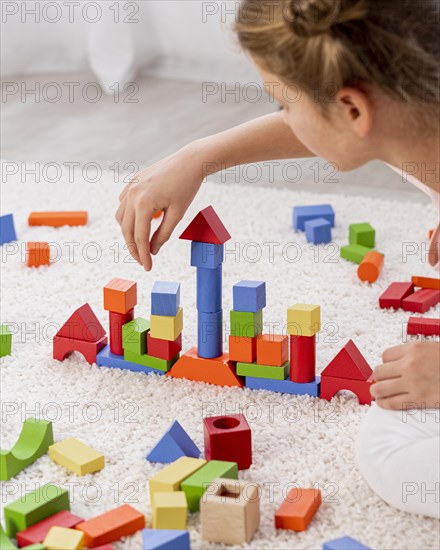 Non binary kid playing with colorful game home