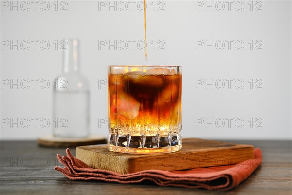 Pouring espresso in glass with tonic and ice cubes