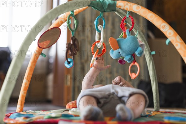 Baby lying developing rug with mobile educational toys