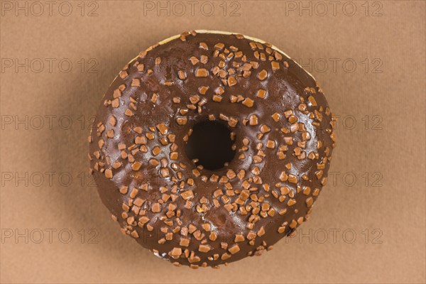 Dark chocolate doughnut with sprinkles brown background