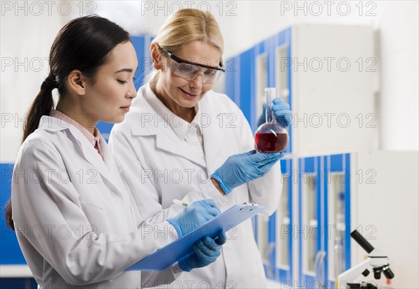 Side view female scientists analyzing substance lab