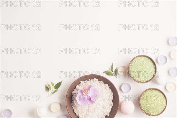 Green white herbal sea salt with many small candles white backdrop