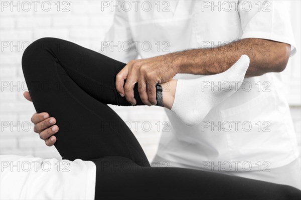 Male physiotherapist checking woman s leg mobility