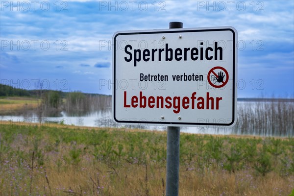 Sign with the inscription Sperrbereich Betreten verboten Lebensgefahr on the shore of Lake Senftenberg