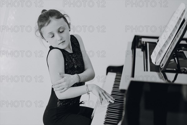 Elegant girl sits at a concert grand piano and plays the piano