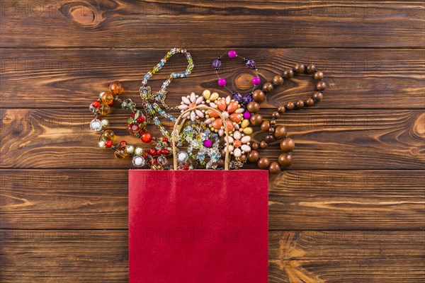 Beads jewelry red paper bag wooden background