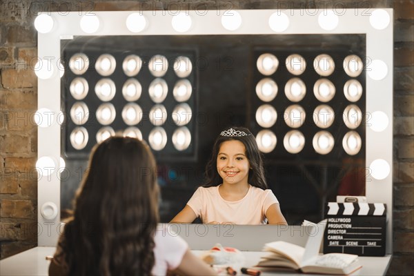 Happy girl looking her reflection mirror backstage