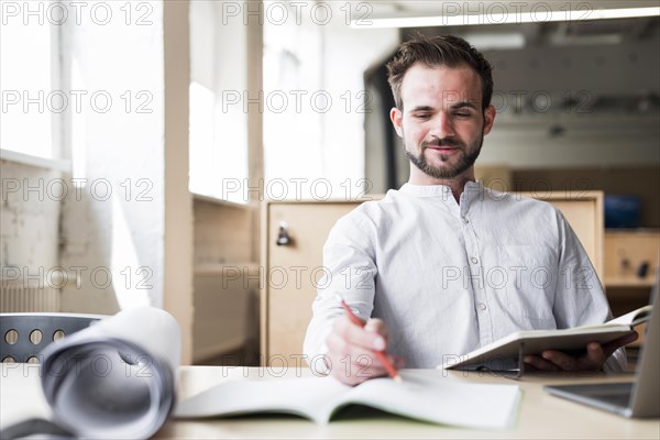 Smiling young man sitting chair working office