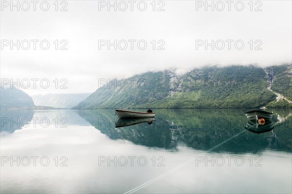 Lonely boats calm lake with misty mountain background