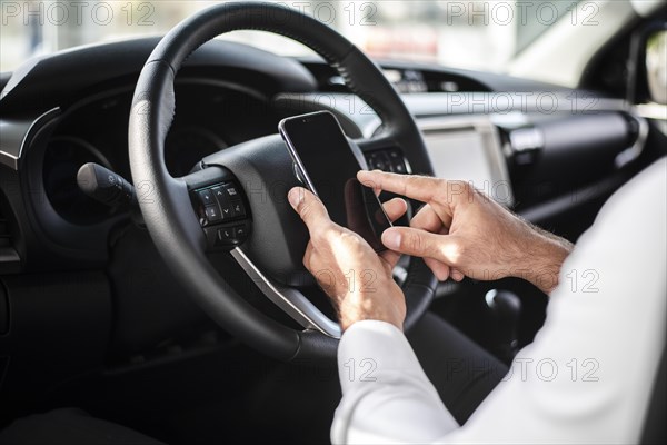 Close up man steer wheel checking phone