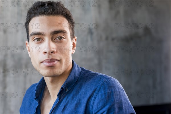 Close up young man looking camera against grey wall