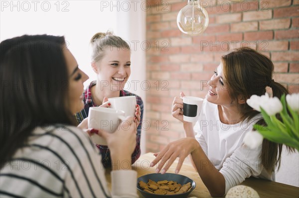 Laughing girls drinking tea talking