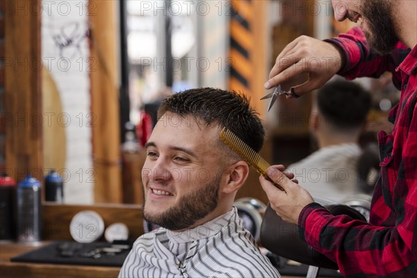 Young man trimming with scissors comb