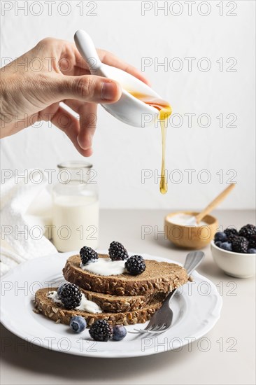Hand pouring honey toast with blueberries