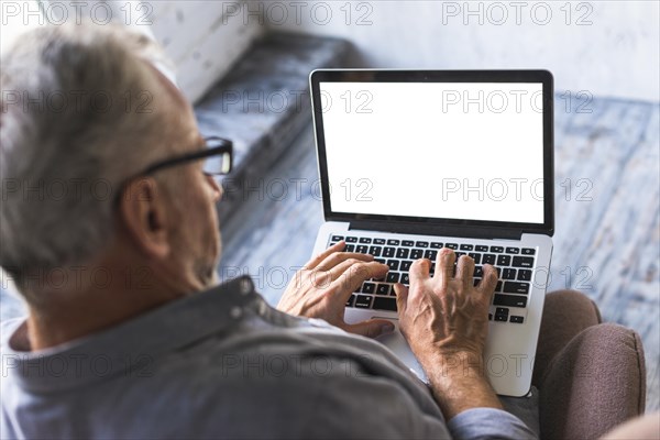 Elevated view man using laptop with white blank screen