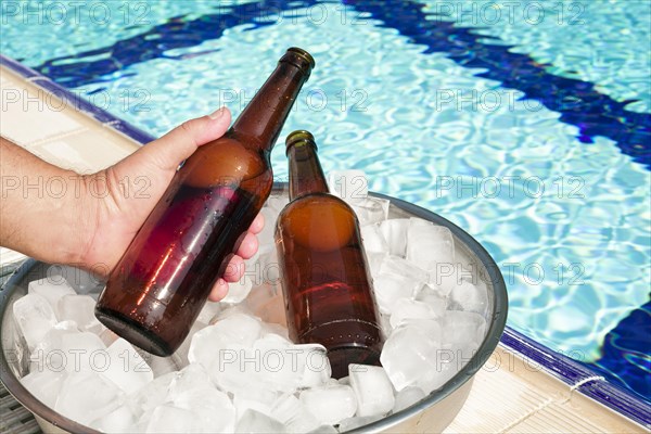 Hand taking out beer bottle out tray with ice