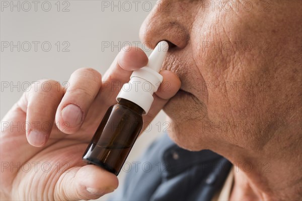 Close up old man using nasal spray