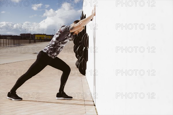 Fitness man doing push ups against wall